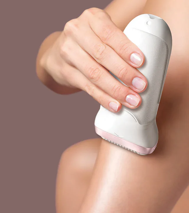Woman using an epilator on her leg for at-home hair removal