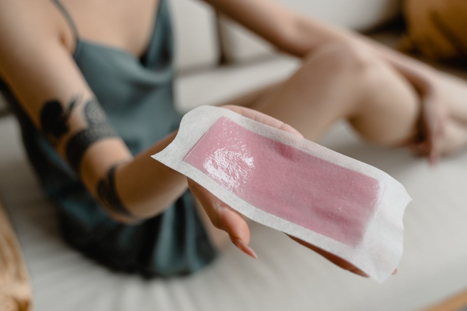 Woman holding a pink wax strip, one option for bikini line hair removal