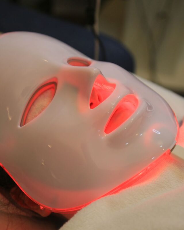 Does red light therapy work: a red LED face mask glowing during a skin treatment