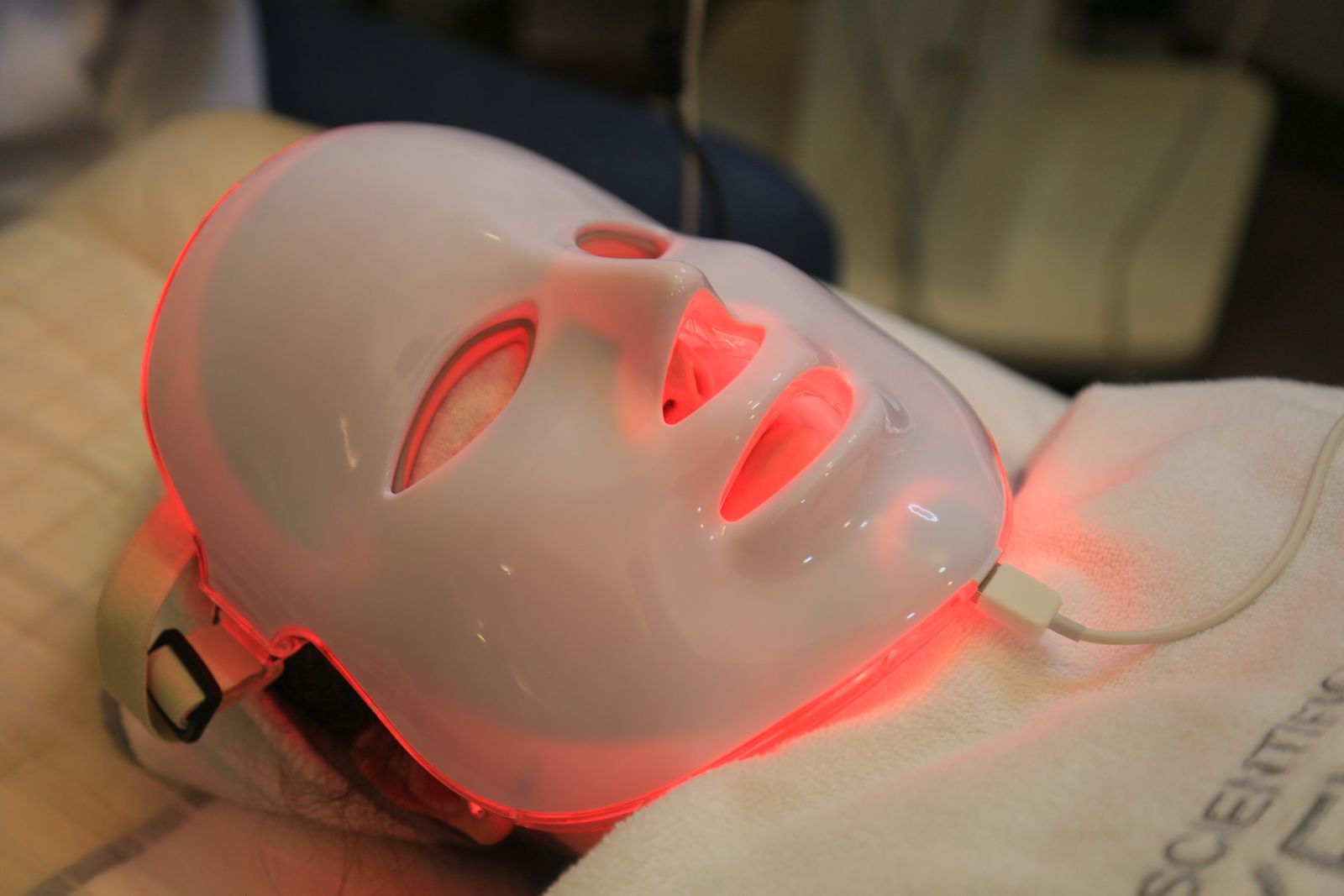 Does red light therapy work: a red LED face mask glowing during a skin treatment