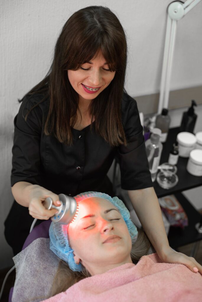 Practitioner using a handheld red light therapy device on a client in a clinic